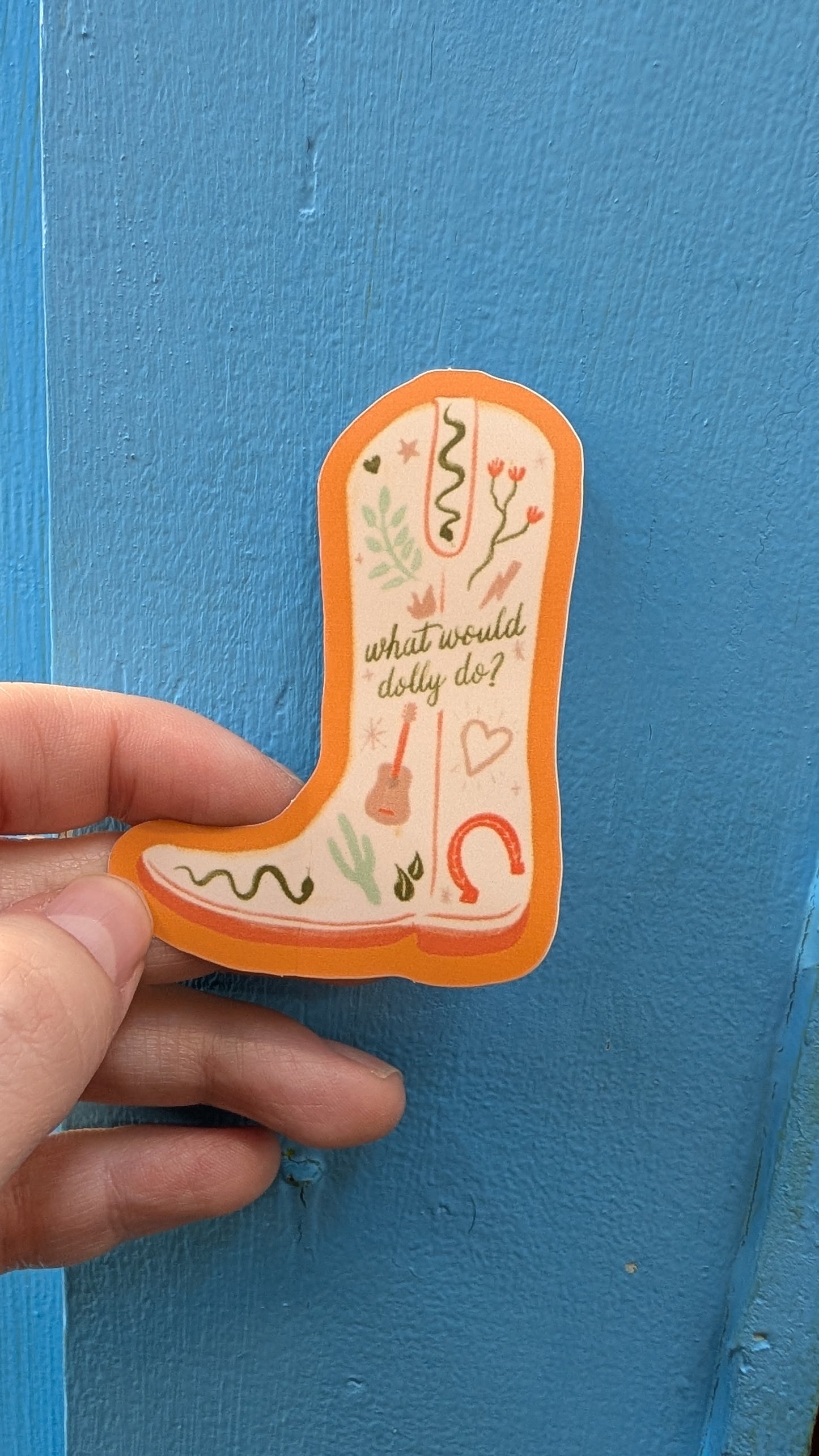 Cowboy boot-shaped sticker with text held against a blue background